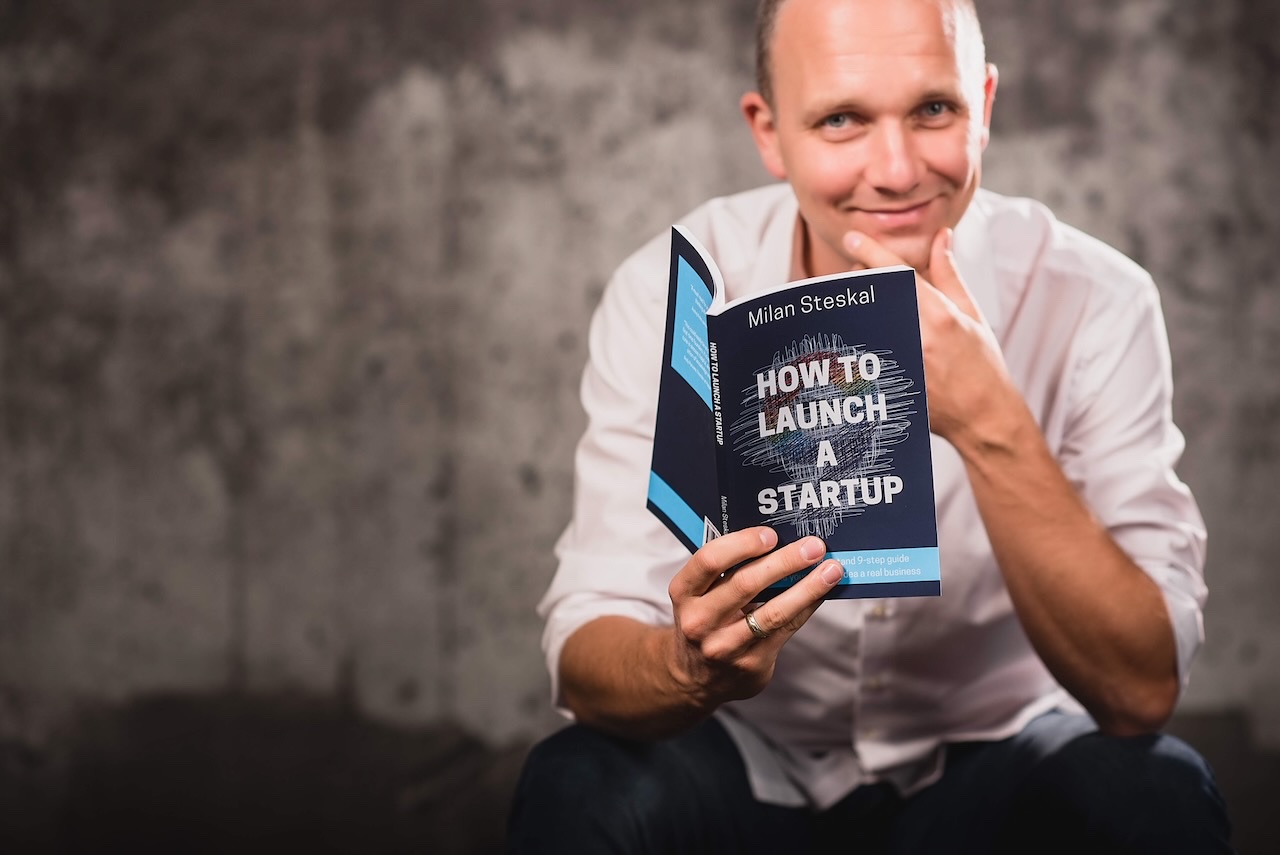 Milan holding his book, How To Launch a Startup