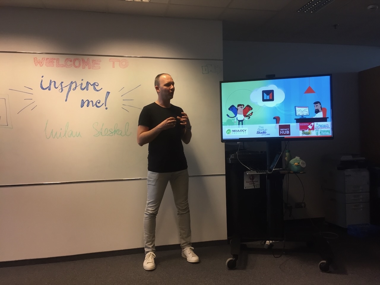Milan speaking at a startup event, with the Mentegram logo on screen